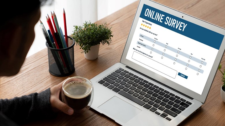 Een man kijkt naar laptopscherm met online enquête in beeld