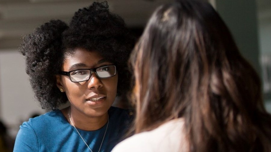 Vrouw zit tegenover andere vrouw en voert gesprek.