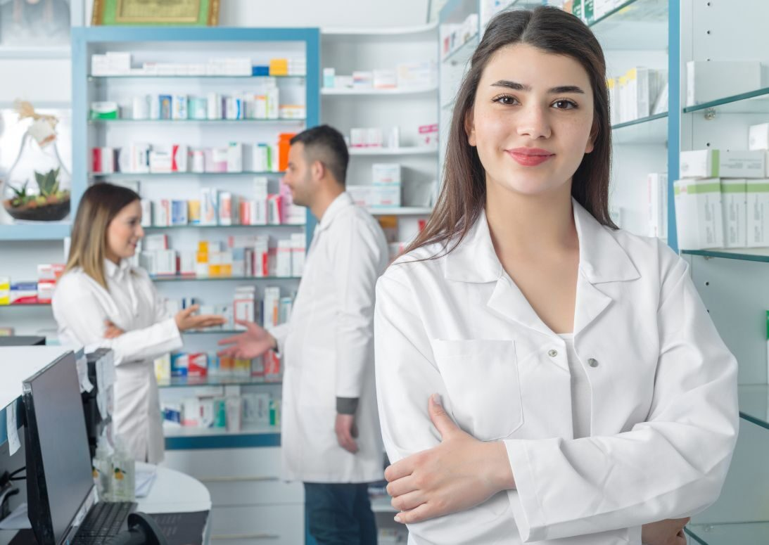 Apothekersassistent aan het werk met 2 collega's op de achtergrond.