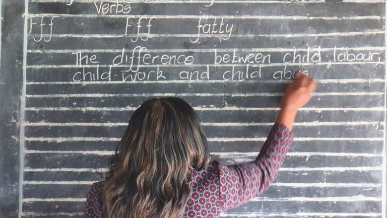 meisje schrijft op schoolbord "the difference between child labur, child work and child abuse.