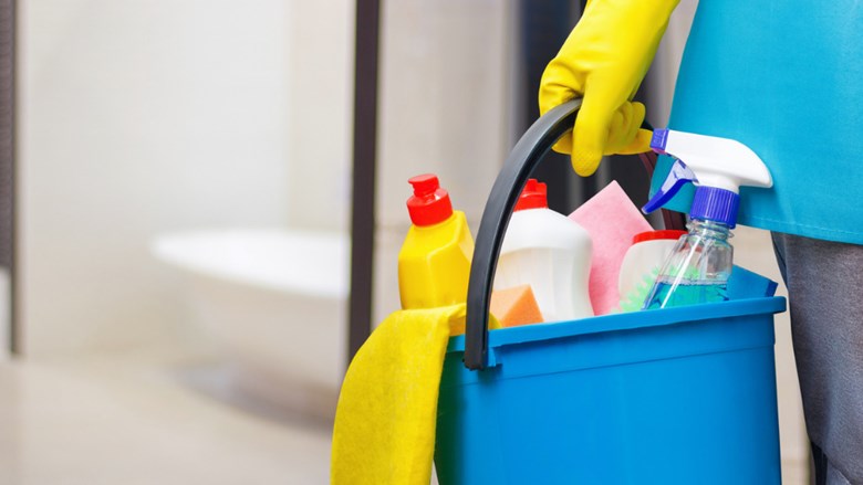 Iemand draagt een emmer met schoonmaakmiddelen