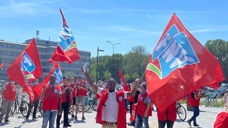 mannen zwaaien met fnv actievlaggen