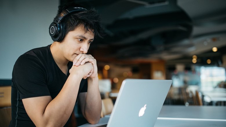 man met koptelefoon achter laptop