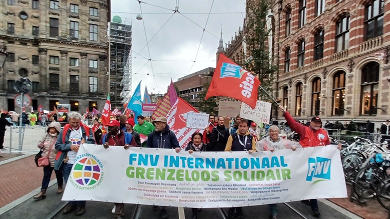 Mensen lopen op straat achter een grote FNV banner