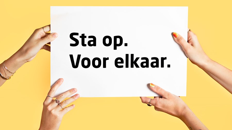 Twee paar handen houden poster vast met de tekst:  Sta op. Voor elkaar.