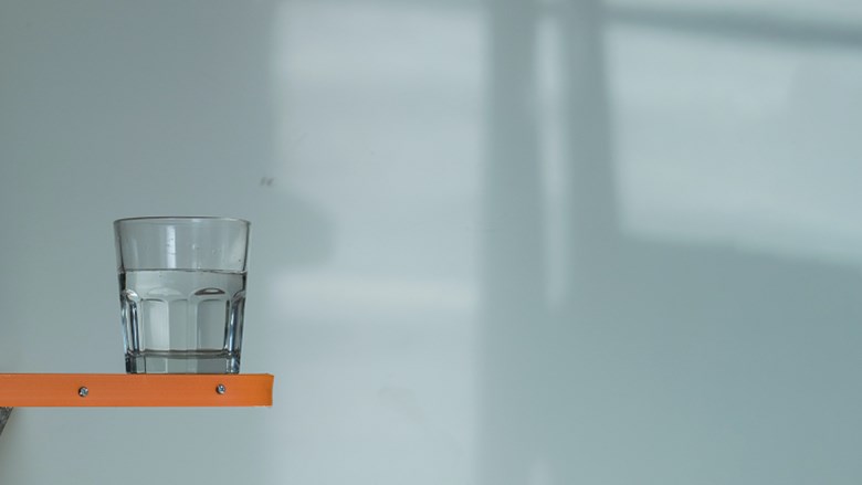 glas water op randje van tafel