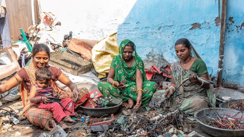 vrouwen zitten op de grond en halen materialen uit de schepen uit elkaar