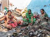 vrouwen zitten op de grond en halen materialen uit de schepen uit elkaar
