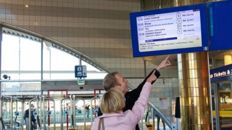 Reizigers bij een NS-bord